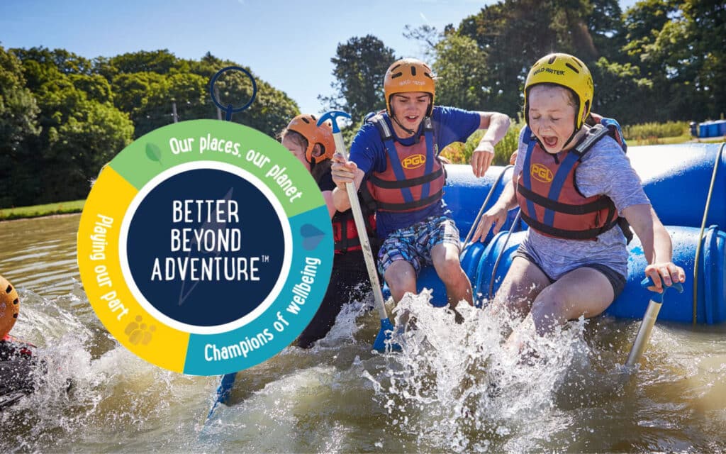 Three young people wearing life jackets and helmets paddle vigorously in a raft, splashing through water, with a colorful logo advertising 