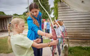 PGL instructor teaching a girl how to fire a bow and arrow