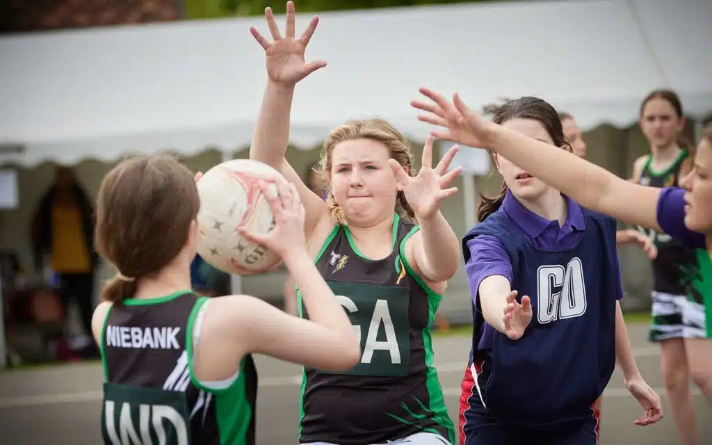 Young female netball players in action, competing for the ball during an outdoor game.