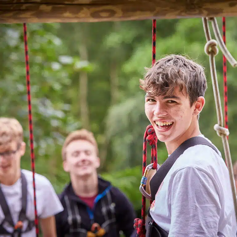 Teenager in harness on kids camp activity session