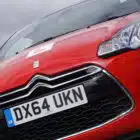 Red Learner Driver car with a Liddington "L" plate displayed on the windshield, registration plate reading "DX64 UKN," shot from a low angle.