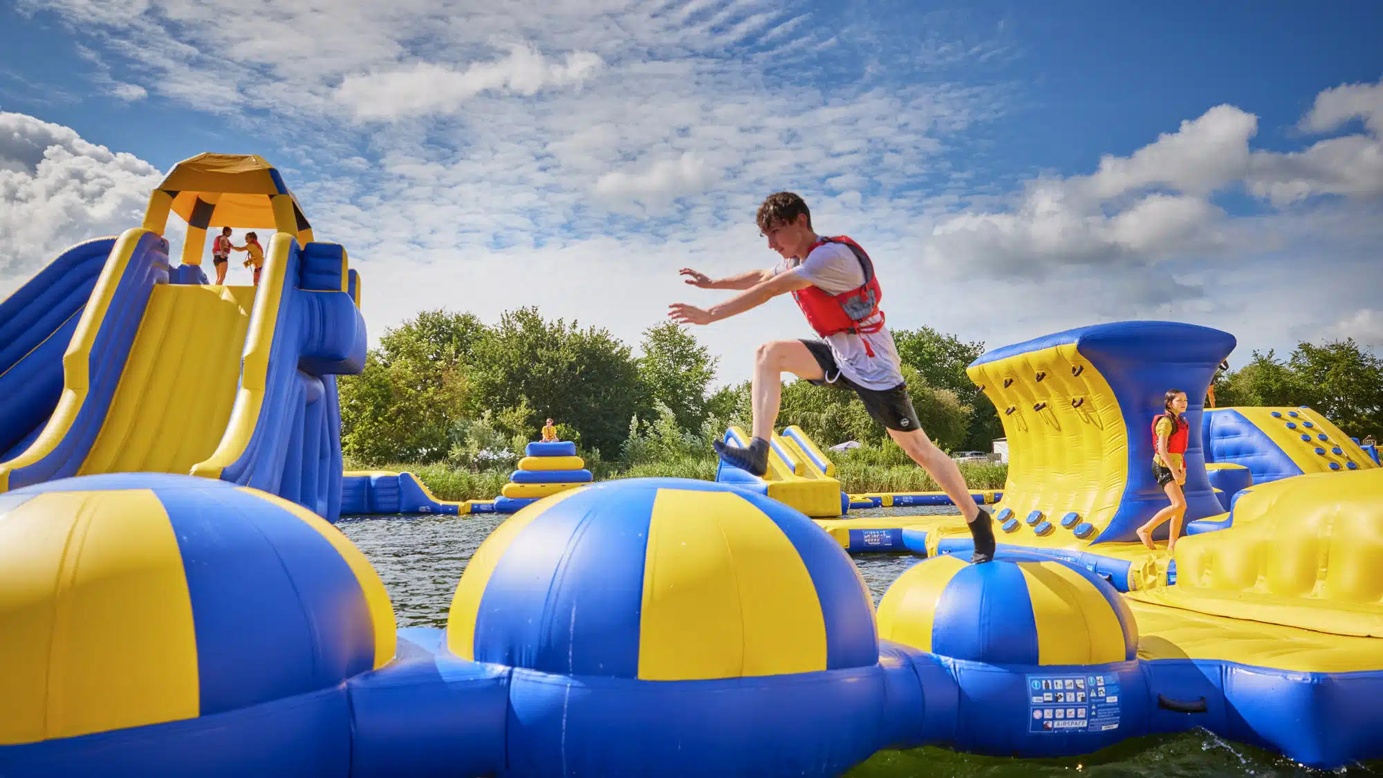 Boy leaping over inflatable water obstacles