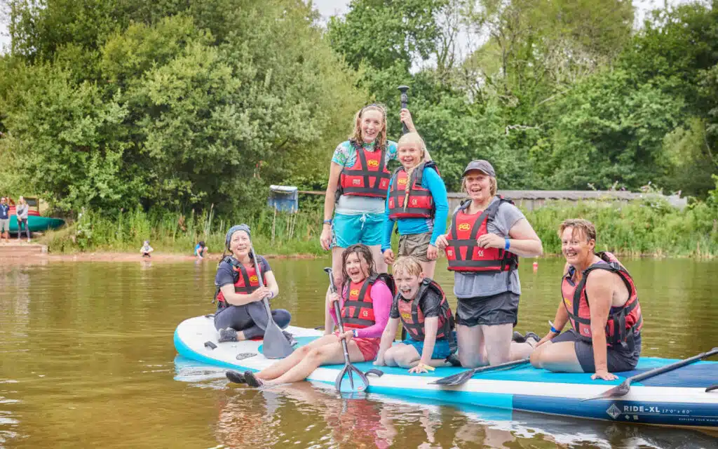 family on a giant stand up paddle board