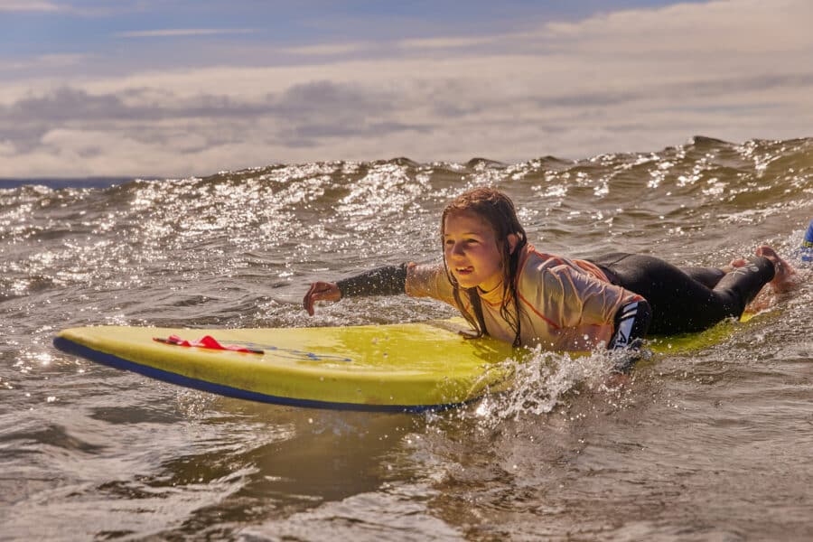 girl learning to surf with a PGL instructor
