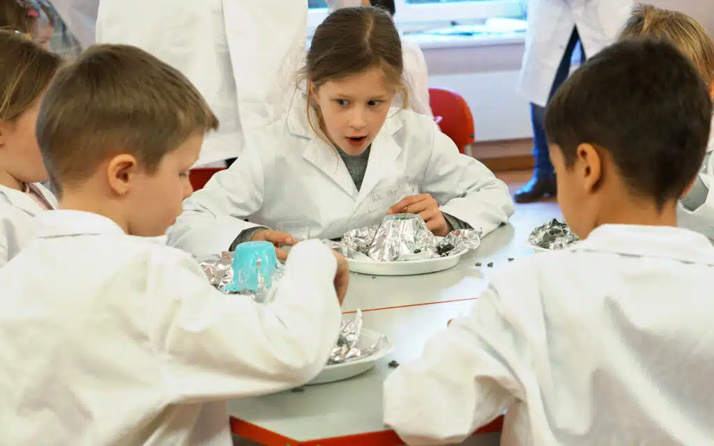 children in lab coats make volcanoes