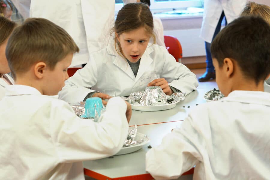 children in lab coats make volcanoes