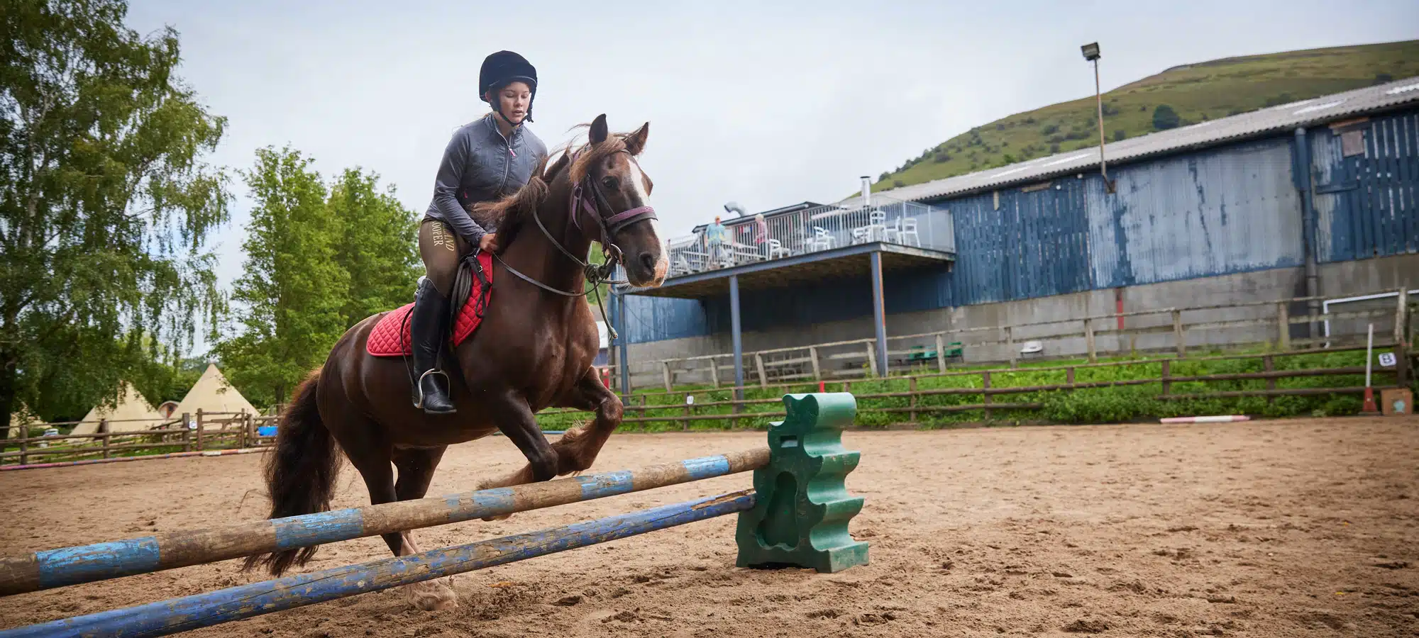 a girl on horseback jumping over a small fence