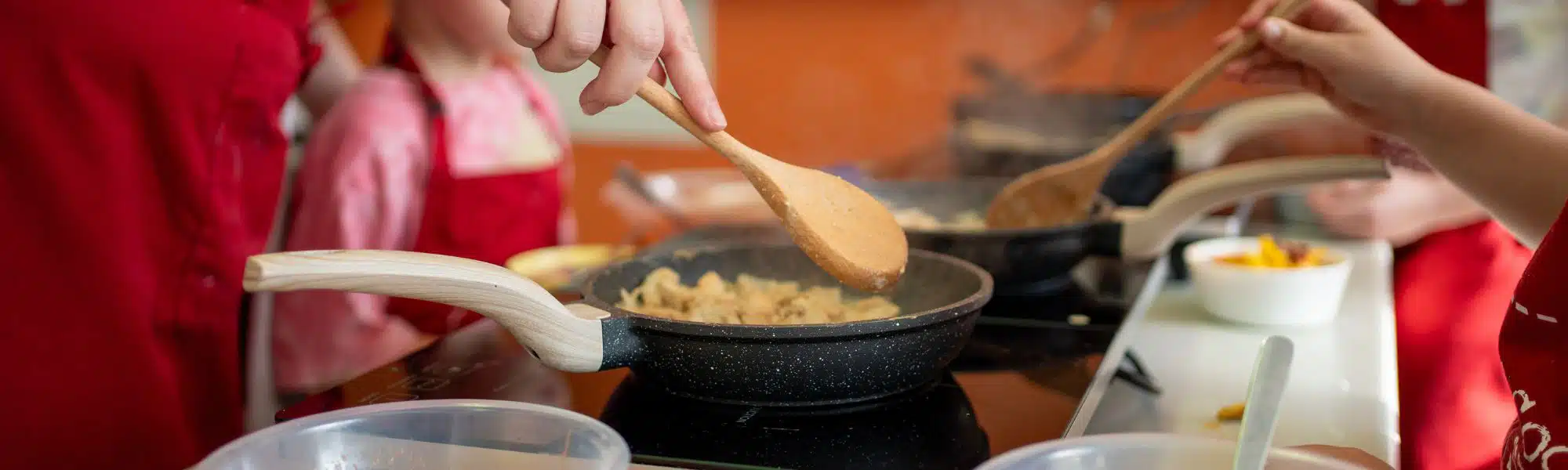wooden spoon stirring food in a frying pan
