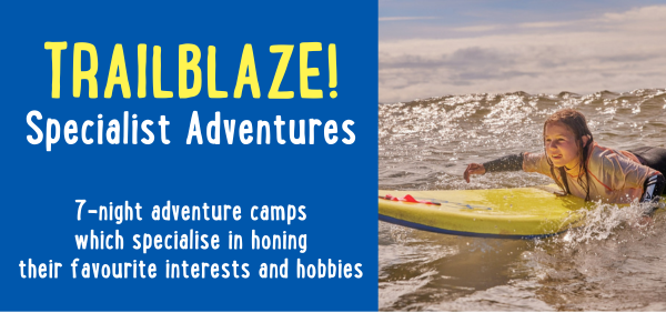 Advertisement for Trailblaze! Specialist Adventures featuring a child on a yellow surfboard in the ocean. Text promotes 7-night adventure camps focusing on honing interests and hobbies.