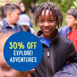 A child smiles at the camera in a group of children outdoors. A blue circle on the image reads "30% OFF EXPLORE! ADVENTURES.