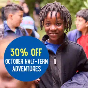 Group of children outdoors with a text overlay reading "30% OFF October Half-Term Adventures.