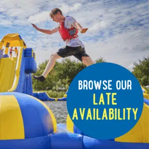 A person wearing a red life jacket jumps on inflatable water obstacles; a blue circle displays the text "Browse our late availability.