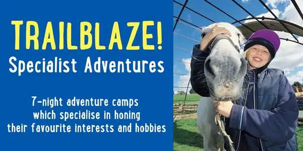 A child wearing a helmet smiles and hugs a horse outside; text promotes Trailblaze specialist adventure camps for kids’ interests and hobbies.