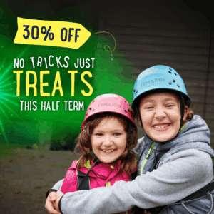 Two smiling children in helmets and outdoor gear embrace, with text overlay: "30% Off. No Tricks, Just Treats This Half Term.