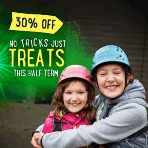 Two smiling children in helmets and outdoor gear embrace, with text overlay: "30% Off. No Tricks, Just Treats This Half Term.