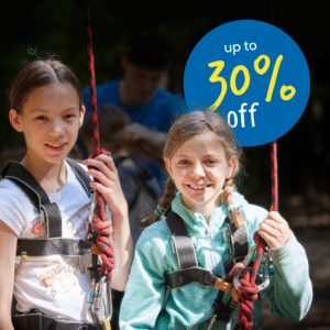 Two girls wearing harnesses and holding ropes, standing outdoors. A blue circle in the background displays the text "up to 30% off.
