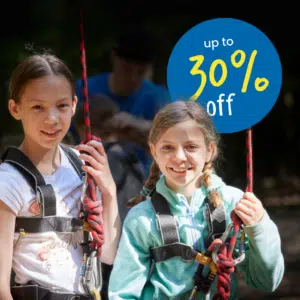 Two girls wearing harnesses and holding ropes, standing outdoors. A blue circle in the background displays the text "up to 30% off.