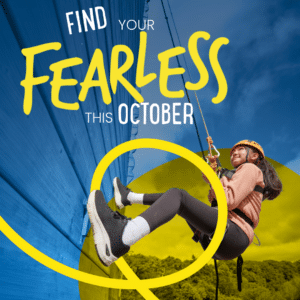 A young woman in safety gear climbs a blue wall outdoors. Text reads, “Find your fearless this October.” Yellow design elements overlay the image.