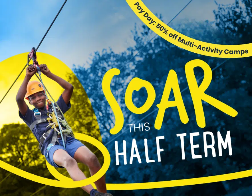 Child ziplining outdoors, wearing a helmet and harness on an exciting PGL Adventure Holidays experience. Text reads: “SOAR THIS HALF TERM. Pay Day: 50% off Multi-Activity Camps.” Background shows trees and blue sky.